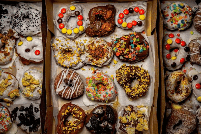 A variety of colorful, decorated doughnuts displayed in an open box.